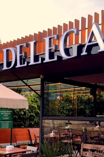 Letreiro do Delega sobre o ripado de madeira da fachada
