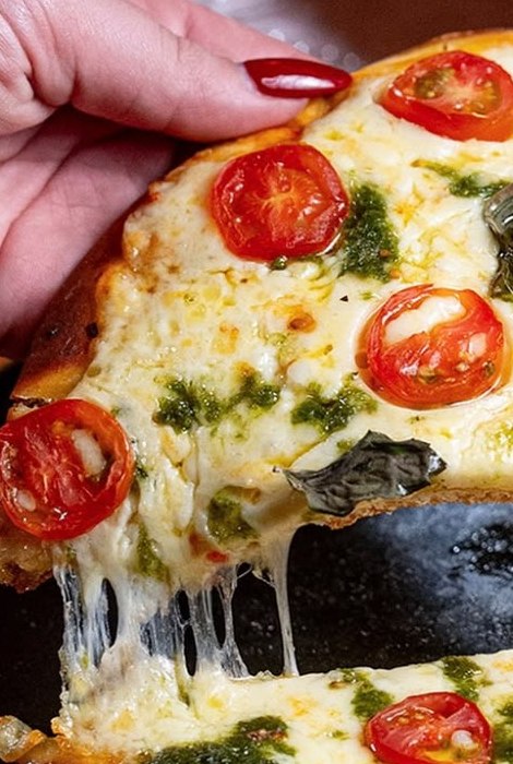 Fatia de pizza de tomate-cereja com pesto sendo servida